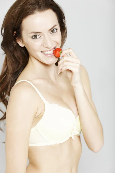 Frau in Unterwäsche isst Erdbeere — Stockfoto