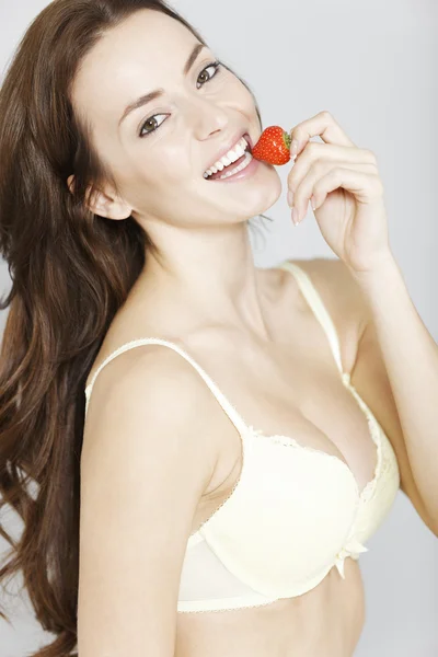 Kvinnan i hennes underkläder äta jordgubbar — Stockfoto