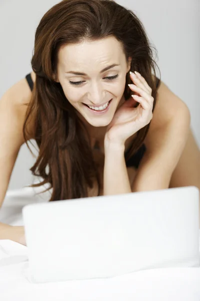 Frau benutzt Laptop im Bett — Stockfoto