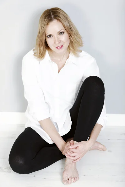 Woman sitting against wall — Stock Photo, Image