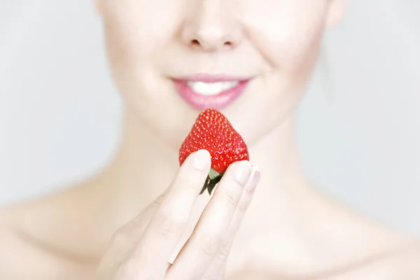 Woman holding up a strawberry — Stock Photo, Image