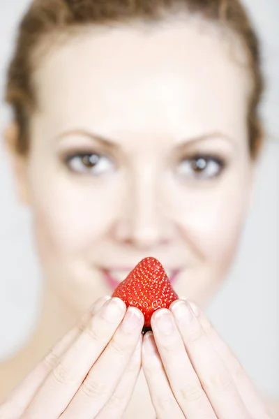 Kvinnan håller upp en jordgubbe — Stockfoto