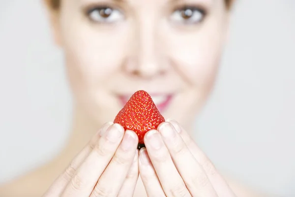 Woman holding up a strawberry — Stock Photo, Image