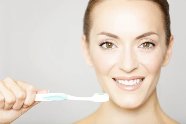 Mujer sonriendo sosteniendo el cepillo de dientes — Foto de Stock