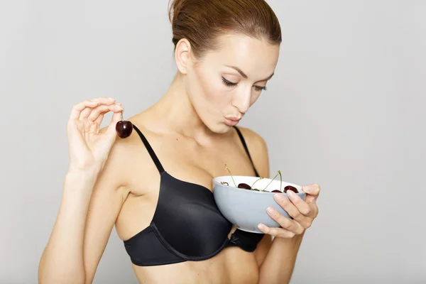 Woman in underwear eating cherries — Stock Photo, Image