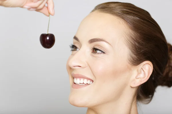 Mulher segurando e comendo cerejas frescas — Fotografia de Stock