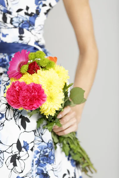 Vista cortada de pernas de mulher segurando flores — Fotografia de Stock