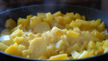 Close up shot of freshly diced yellow potatoes sizzling in a hot skillet, creating a delicious aroma as they cook in hot oil, capturing the essence of a cozy homemade meal being prepared