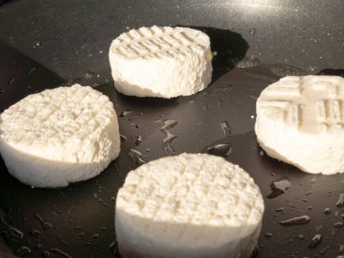 Goat cheese rounds frying in a nonstick pan, forming golden crusts and a creamy center  perfect warm appetizer or salad topper for simple, gourmet home cooking