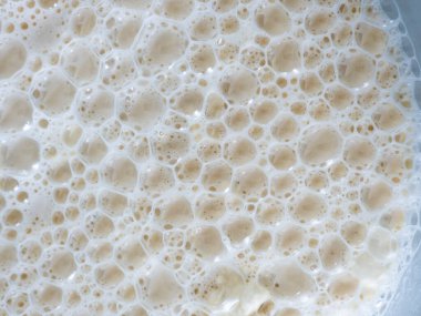 Close up macro view of intricate foamy bubbles forming a complex repeating pattern, illustrating the texture and surface of an effervescent liquid creating a natural abstract background