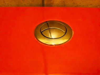 Klozet düğmesi, canlı kırmızı ve pirinçten renk paleti içinde su koruma ve çevre dostu tuvalet çözümleri sunan ikili sifon için bölünmüş bir tasarıma sahiptir.