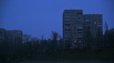 Kasvetli mavi gökyüzünde parlayan yıldırımlar ile dramatik fırtınalı bir hava. Şehir binalarının üzerinde, gece güçlü bir fırtına sırasında, ürkütücü bir parıltıyla şehri aydınlatıyor.