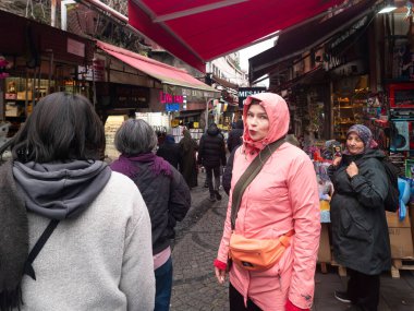 İstanbul, Türkiye - 8 Aralık 2025, İstanbul 'da dar bir kaldırım taşı caddesinde kalabalık bir açık hava pazarını keşfeden insanlar, kırmızı tentelerin altındaki satıcılara bakıyorlar.