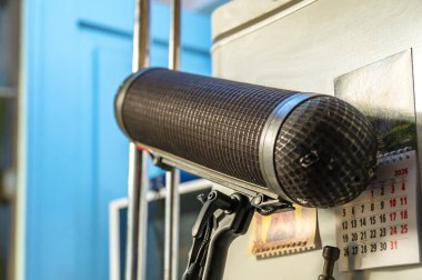 Profesyonel pompalı mikrofon, balon ön camına monte edilmiş, iç mekandaki sesleri yakalıyor, ses üretimini, yayıncılığı ve podcast 'i sembolize ediyor.