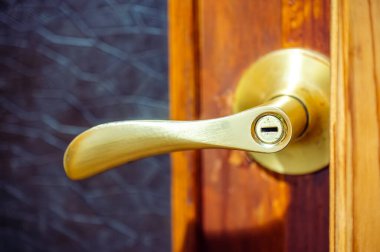 Ahşap kapıda görünür anahtar deliği olan pirinç kapı kolu, güvenlik, ev veya ofis girişi için erişim ve mahremiyet sembolize eden kapatma, klasik metal donanım detayı