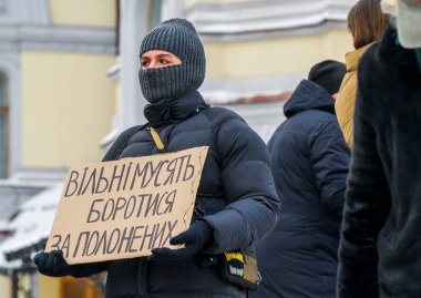 Kyiv, Ukrayna - 25 Ocak 2026: Kar maskesi takan protestocu, Ukraynalı savaş esirlerinin serbest bırakılmasını savunan mitingde el yapımı bir tabela tutuyor.