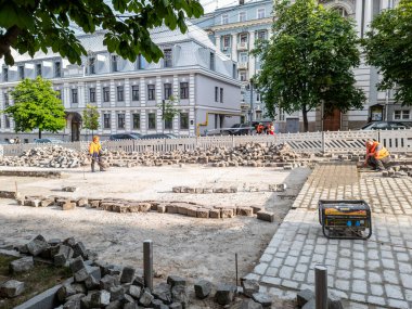 Kyiv, Ukrayna - 14 Haziran 2023: Çelik yelek giyen inşaat işçileri kaldırım taşları döşüyorlar ve kentsel yenilenme sahasının zeminini hazırlıyorlar, altyapı gelişimini ve kentte devam eden gelişmeleri sergiliyorlar