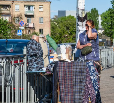 Kyiv, Ukrayna - 12 Mayıs 2022: Bir açık hava pazarında ikinci el giysi ve çeşitli ürünler satan bir sokak satıcısı, Kyiv kaldırımında, yaz günü