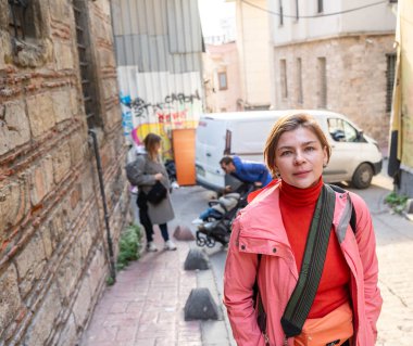 Güneşli bir günün tadını çıkaran kadın gezgin, İstanbul 'un tarihi bir bölgesinde geleneksel bir kaldırım taşı caddesini keşfediyor, yerel atmosferi ve kültürü deneyimliyor.