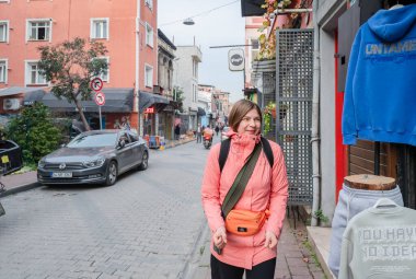 Parke taşlı bir sokakta yürürken sırt çantasıyla gezen ve gülümseyen bir kadın. Canlı bir şehir bölgesinde tek başına seyahat ve tarihi bir şehir ortamını gezmenin tadını çıkarıyor.