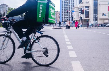 Kyiv, Ukrayna - 6 Mayıs 2023: Kyiv caddesinde bisiklet süren Bolt Food Courier, yayaların ve trafiğin içinden hızla geçerek emirleri iletiyor.