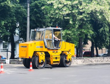 Kyiv, Ukrayna - 6 Mayıs 2023: Sarı yol pateni Kyiv Podil kentsel caddesinde taze asfalt sıkıştırıyor, gündüz vakti yol yapımı ve altyapı iyileştirme projesi