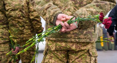 Kyiv, Ukrayna - 29 Ocak 2026: Kamuflaj üniformalı askerler arkalarında kırmızı karanfiller taşıyorlar, Kruty kahramanlarını anıyorlar, onuru ve hatırayı simgeliyorlar