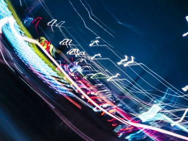 Soyut renkli ışık izleri koyu mavi tuval boyunca dinamik bir bulanıklık çizer, bir gece saatinde hız, kentsel enerji ve teknolojik bağlantı kavramlarını anımsatır.