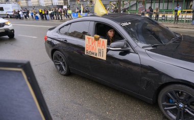 Kyiv, Ukrayna - 16 Şubat 2026: Kadın arabasında Ukraynalı askerlerin özgürlük çağrısında bulunurken, şehir sokaklarında savaş esirleri ve adalet için düzenlenen protesto mitinginin önünden geçiyor