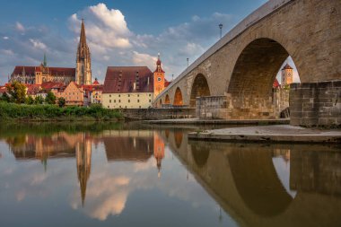 Regensburg, Almanya. Almanya 'nın Regensburg şehrinin Tuna Nehri üzerindeki Eski Taş Köprüsü ve St. Peter Katedrali' nin yaz günbatımında görüntüsü.