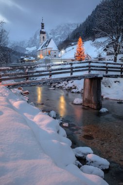 Alplerdeki Kış Harikalar Diyarı. Noel zamanı Bavyera Alpleri 'nin manzara görüntüsü, St. Sebastian Kilisesi Ramsau bei Berchtesgaden, Almanya' da güzel kış günbatımında yer almaktadır..