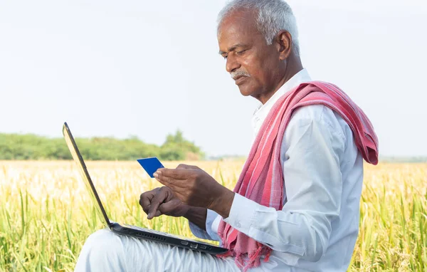 Indiase boer op laptop doet betaling met behulp van credit card - concept van landelijke mensen met behulp van technologie, internet en levensstijl. — Stockfoto