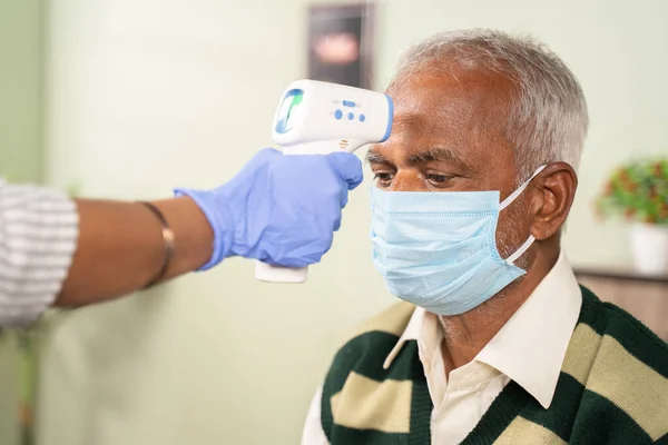 코로나 바이러스 (coronavirus) 코로나 바이러스 (covid-19) 안전 조치로 얼굴에 마스크를 쓰고 있는 동안 병원에서 환자의 체온을 확인 한다.. — 스톡 사진