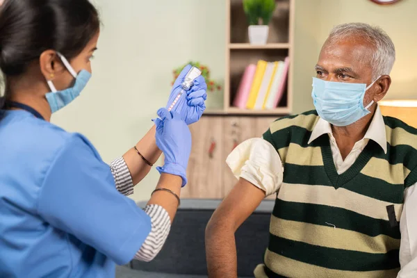 Doktor, yaşlı hastaya Coronavirus covid-19 salgını sırasında ev sağlığı kontrolü konseptini elinde tutarak aşı hazırlıyor..