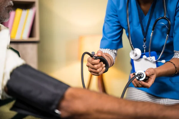Médico o enfermera irreconocible que revisa la presión arterial o la presión arterial del paciente en casa. —  Fotos de Stock