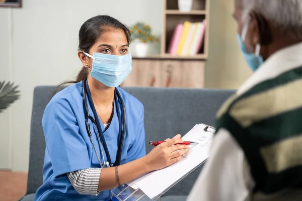 Omuz aşısı, genç doktor ya da hemşire hasta yaşlı adamı ziyaret ederken reçete yazarken, her ikisi de güvenlik önlemi olarak koronavirüs covid-19 salgınından dolayı maske takıyordu.