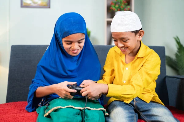 Брат-мусульманин крадет геймпад у сестры, чтобы играть в видеоигры дома - Концепция борьбы братьев и сестер детства — стоковое фото