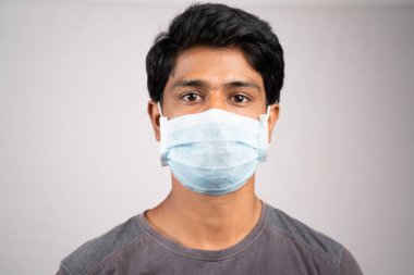 Genç adam yüz maskesi ile burun ve ağzı düzgün bir şekilde örttü - Koronavirüsten ya da izole bir arka plandaki Cvid-19 krizinden korunmak için maske takmak için farkındalık ve güvenlik kavramı.