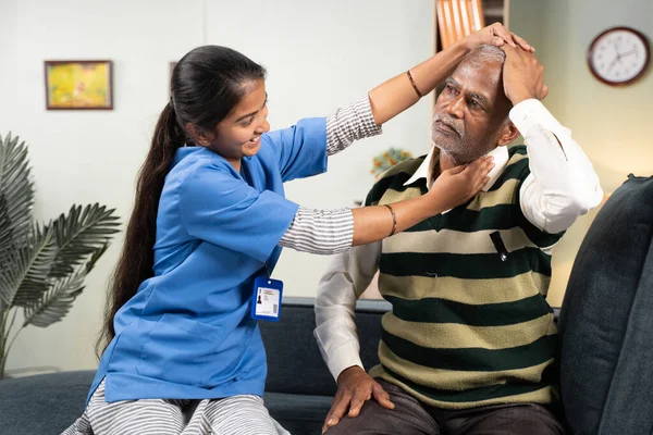高齢者の在宅医療やサービスの概念-医師や看護師は、自宅で患者の頭を回転させることによって首の運動のための高齢者を支援. — ストック写真