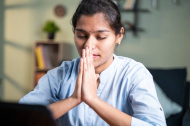 Genç iş kadını çevrimiçi test bittikten sonra dizüstü bilgisayarın önünde dua ediyor ya da sonuçlar için muayene oluyor - inanç kavramı, Tanrı 'ya şükran