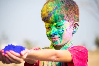 Holi festivali kutlaması konseptine renk katan Holi pudrası dolu gülümseyen çocuğun yan görüntüsü