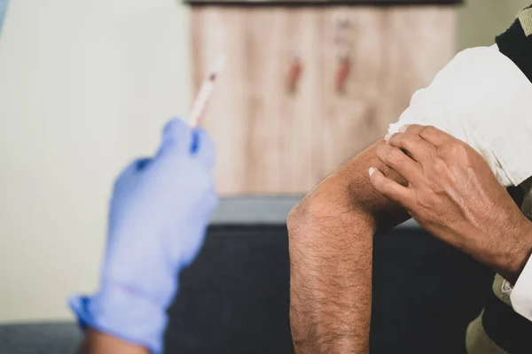 Yaşlı hastaya şırınga ya da mahkeme kararıyla aşı yapılan, evde omzunu ovuşturan - Coronavirus covid-19 aşısı konsepti