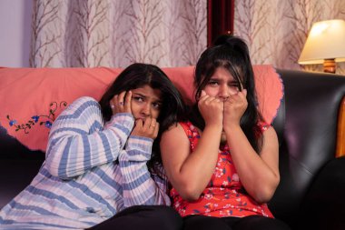 İki korkmuş kız evdeki kanepede otururken korku filmi ya da sinema seyrediyor.