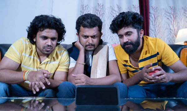 Három indiai fiatal krikett rajongók kezében denevér és labda néz érdekes élő streaming krikett mérkőzés mobiltelefonon otthonról. — Stock Fotó