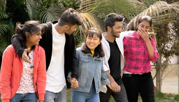 Ομάδα από πέντε χαρούμενους νέους φίλους που γελούν ενώ περπατούν κρατώντας τα χέρια - έννοια της διασκέδασης, οι καλύτεροι φίλοι, η φιλία, η συντροφικότητα και ο τρόπος ζωής κολέγιο — Φωτογραφία Αρχείου