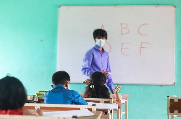중학생, 의료용 마스크를 쓴 교사, 교실에서 코로나 바이러스 (coronavirus) 를 사용하는 제한 된 아이들 과 함께 가르치는 의료용마스크에 집중하라 - 새로운 정상, 교육, 학교 로의 귀환에 대한 개념. — 스톡 사진