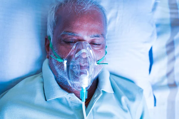 Закройте верхний вид снимка старого дыхания с кислородной маской в больнице из-за коронавирусного ковида-19 одышки или одышки — стоковое фото