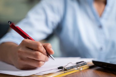 Focus on hand, Close up unrecognizable hands of Young business woman writing down notes at working desk - concept of employee or student online training class or making to do list at home