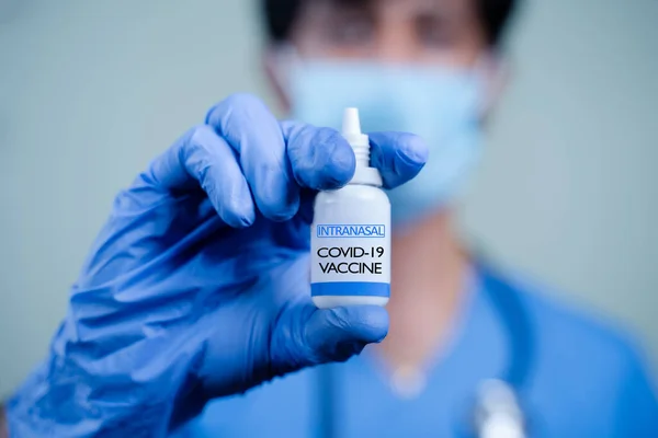 Coronavirus ya da covid-19 salgını için intranasal aşı şişesi tutan doktorun ya da hemşirenin ellerini kapat..