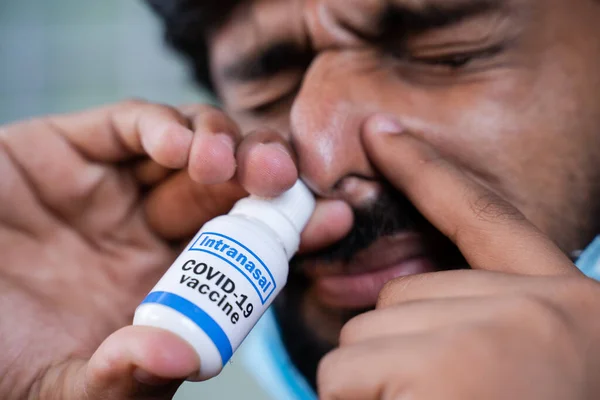 Tıbbi maskeli genç adama aşırı yakın çekim Coronavirus covid-19 geniz aşısı soluyarak virüs enfeksiyonundan korur..